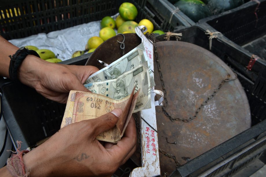 Jemand zählt indische Rupien vor einem Korb.