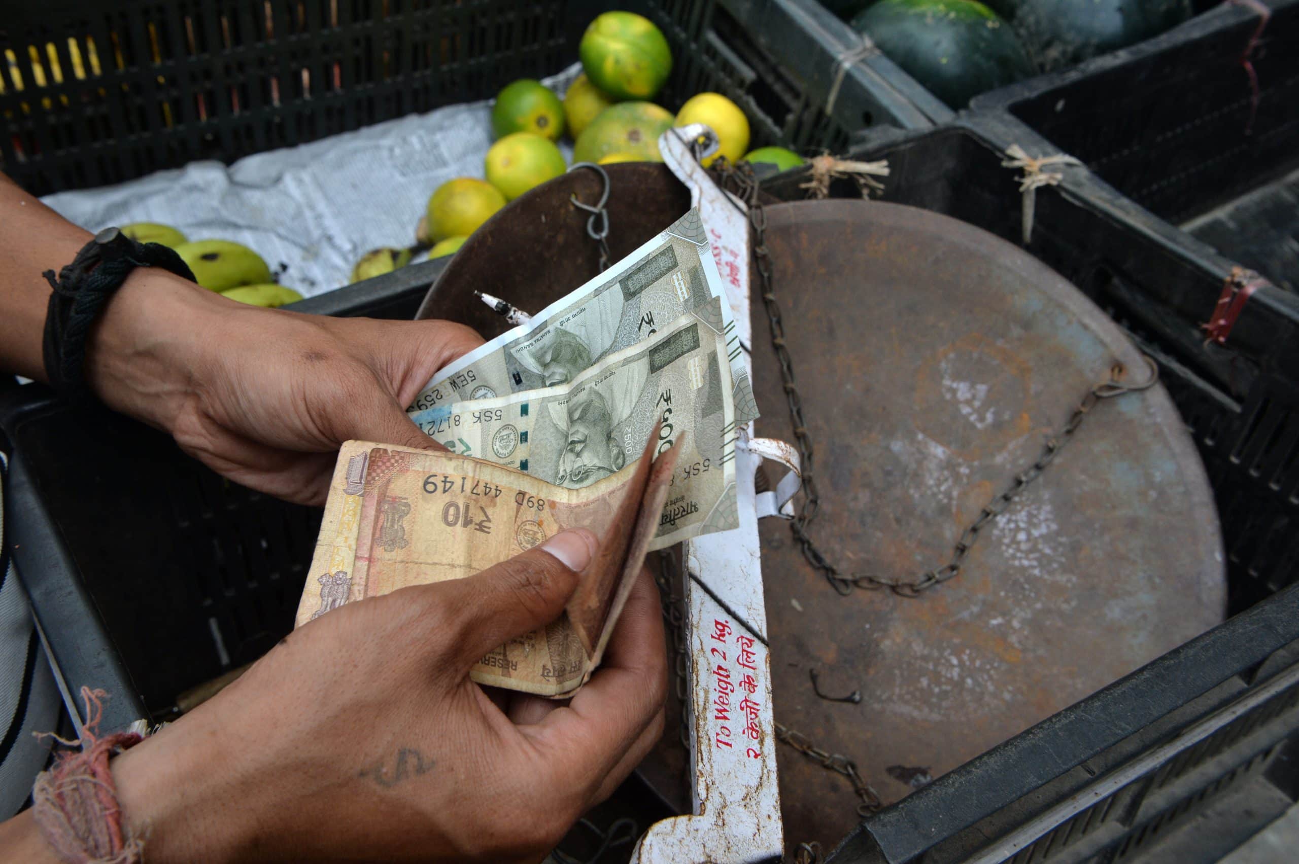 Jemand zählt indische Rupien vor einem Korb.