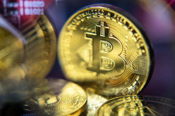 Eine Bitcoin-Münze wird leicht verschwommen angezeigt. Neben ihr sind andere unscharfe Bitcoin-Münzen dargestellt.