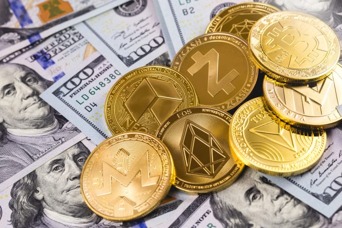 Ein Haufen verschiedener vergoldeter Altcoin-Münzen liegt auf mehreren US-Dollar-Noten.