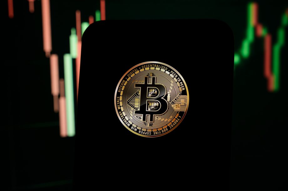 Bitcoin-Münze vor einem Kurschart.