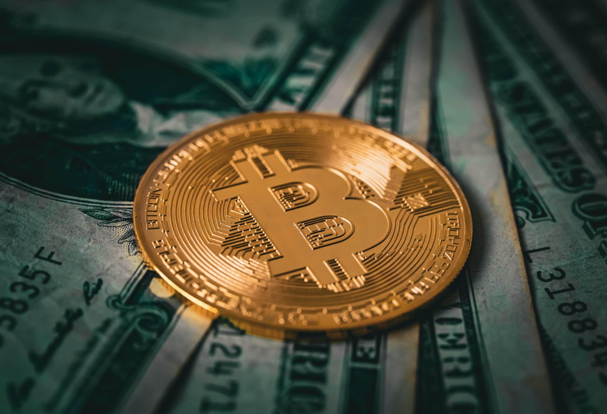 Eine vergoldete Bitcoin-Münze liegt auf verschiedenen US-Dollar-Noten.