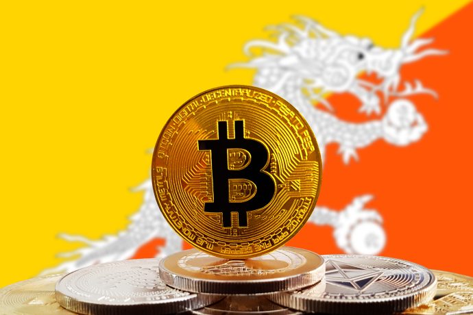 Eine Bitcoin-Münze vor der bhutanischen Landesflagge.