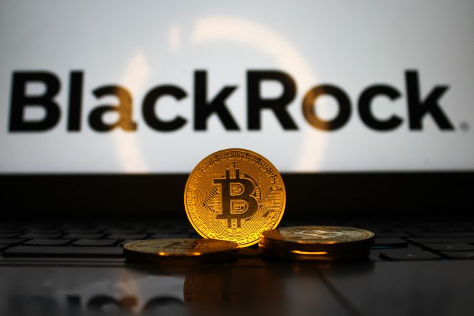 Das Bild zeigt eine Bitcoin-Münze vor dem BlackRock-Logo