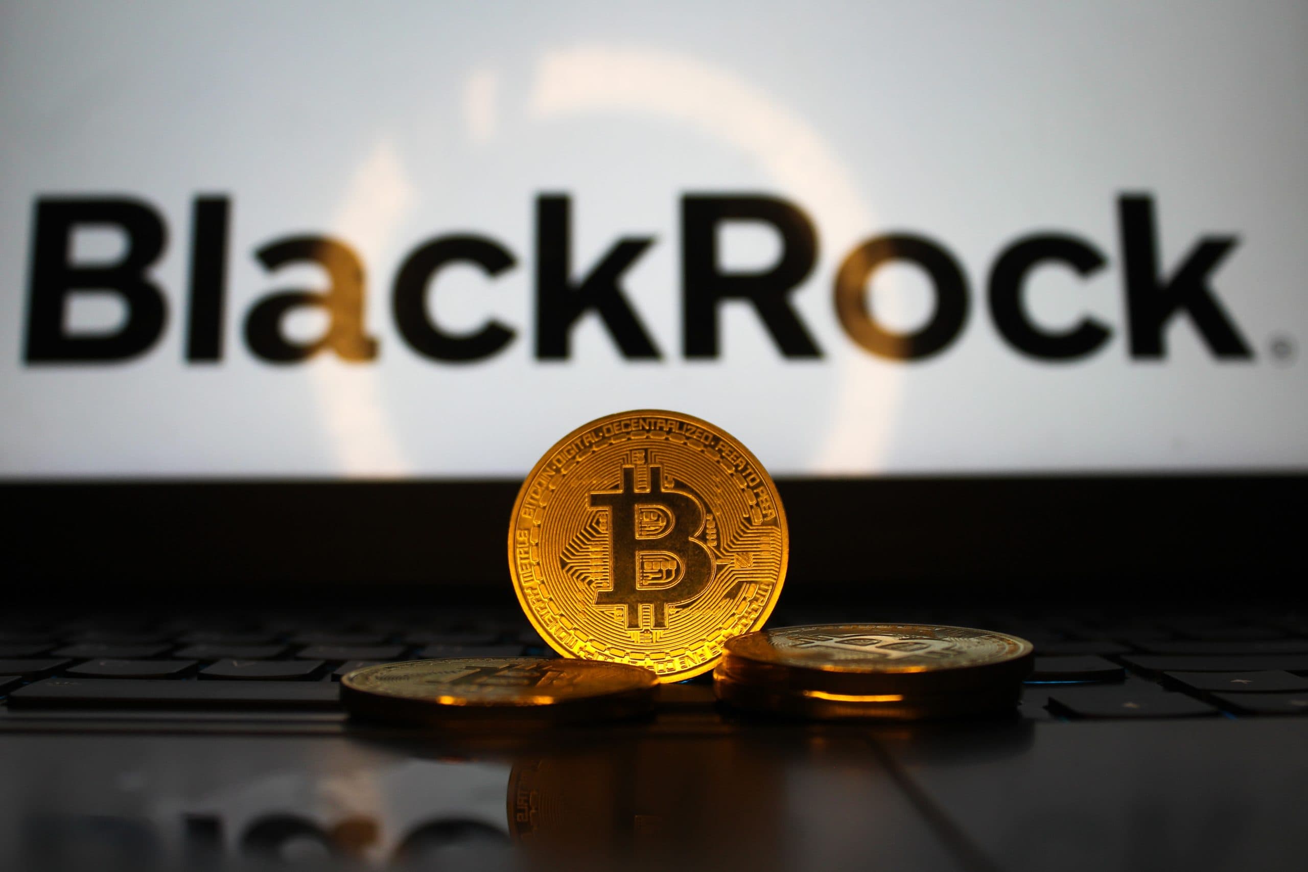 Das Bild zeigt eine Bitcoin-Münze vor dem BlackRock-Logo