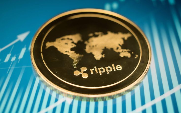 Eine Nahaufnahme einer XRP-Münze mit einem Weltkartenmotiv auf blauem Hintergrund mit Finanzgrafikelementen.