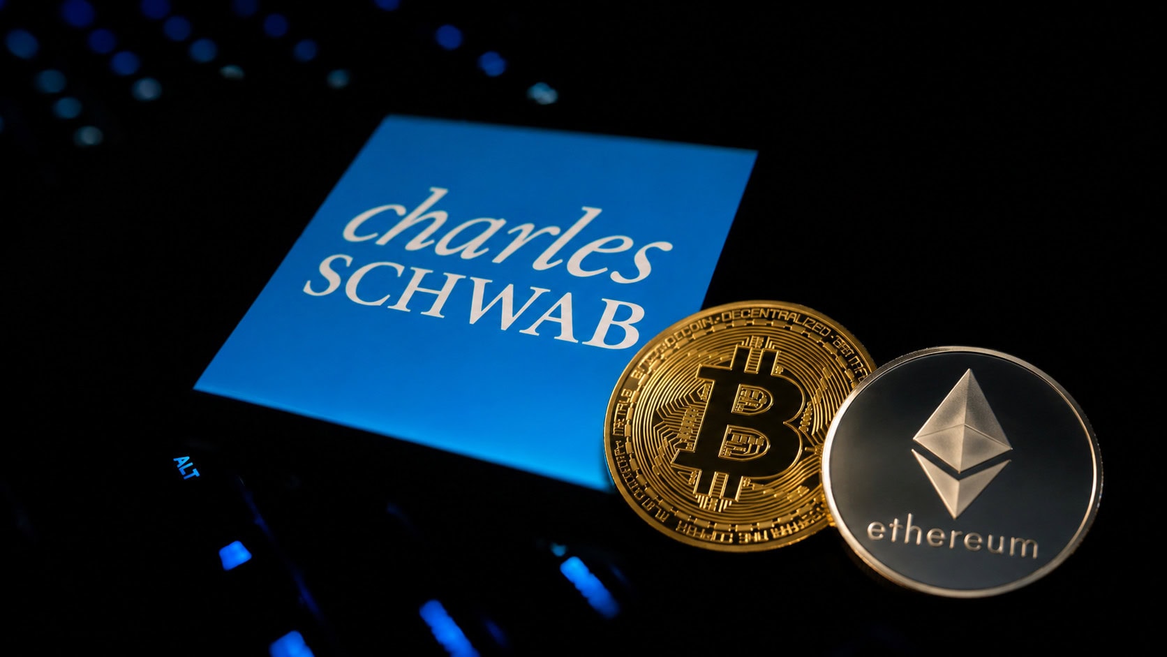 Das Logo von Charles Schwab neben einer Bitcoin- und Ethereum-Münze.