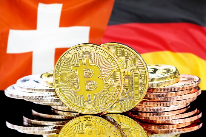 Das Bild zeigt die Flaggen von Deutschland und der Schweiz und im Vordergrund eine Bitcoin-Münze.