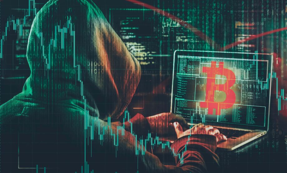 Ein Krypto-Anleger in einem Kapuzen-Sweatshirt nutzt einen Laptop mit großem Bitcoin-Symbol, während digitaler Code und Finanzcharts im Hintergrund auf eine möglicherweise gefährdete Situation hinweisen.