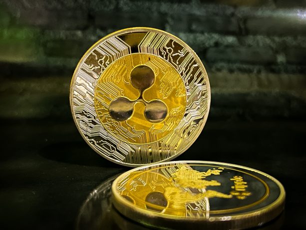 Zwei XRP-Münzen vor dunkelgrünem Hintergrund.