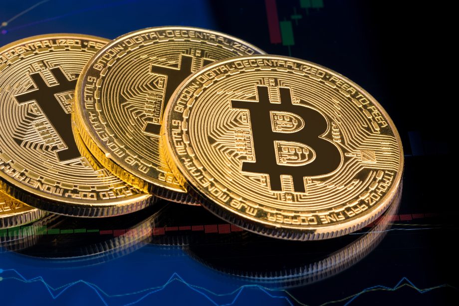 Mehrere goldene Bitcoin-Münzen liegen vor einem Börsenchart mit grünen und roten Kurskerzen. Das Bild symbolisiert die aktuellen Kapitalzuflüsse in Spot-Bitcoin-ETFs und die Entwicklung des Kryptomarkts.