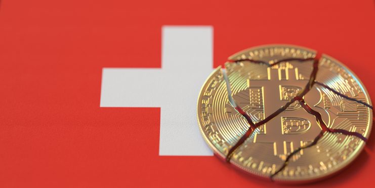 Eine zerbrochene Bitcoin-Münze liegt auf einer Schweizer Flagge