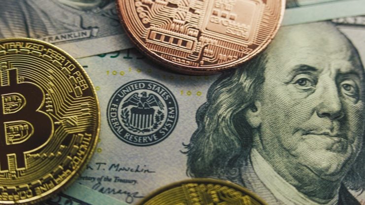 Im Hintergrund befinden sich US-Dollar-Banknoten. Im Vordergrund sind wiederum zwei Münzen abgebildet, die Bitcoin und eine andere Kryptowährung darstellen sollen.