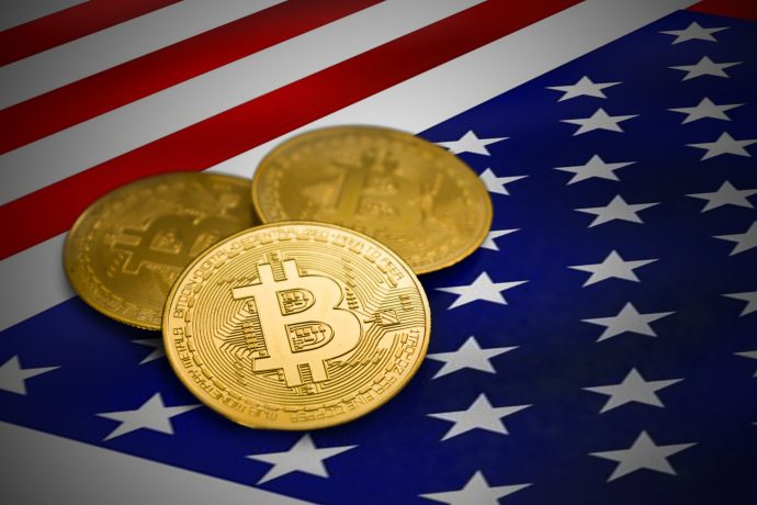 Das Bild zeigt Bitcoin-Münzen auf einer US-Flagge