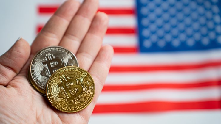 Die Grafik zeigt Bitcoin-Münzen vor einer US-Flagge