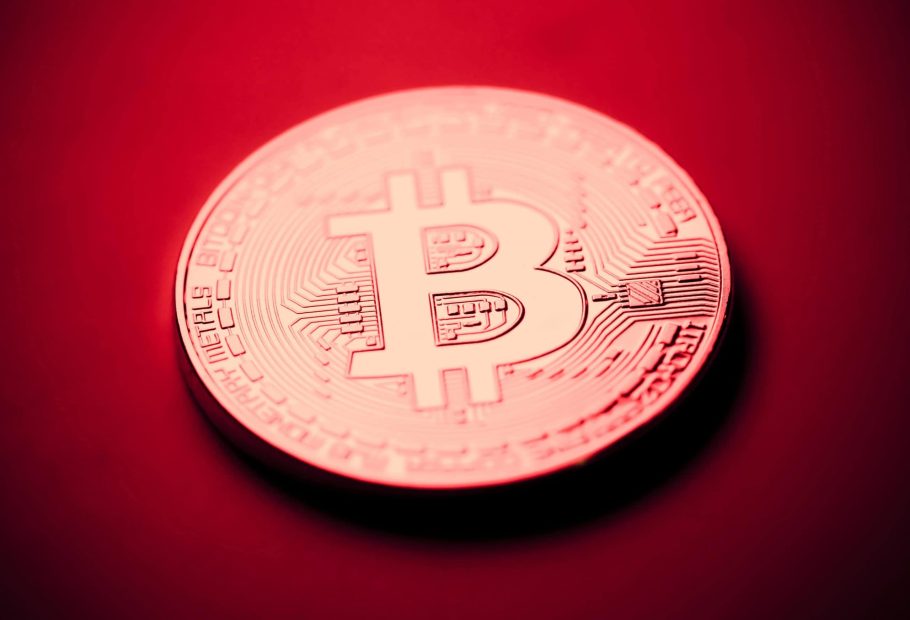 Eine Bitcoin-Münze vor einem roten Hintergrund