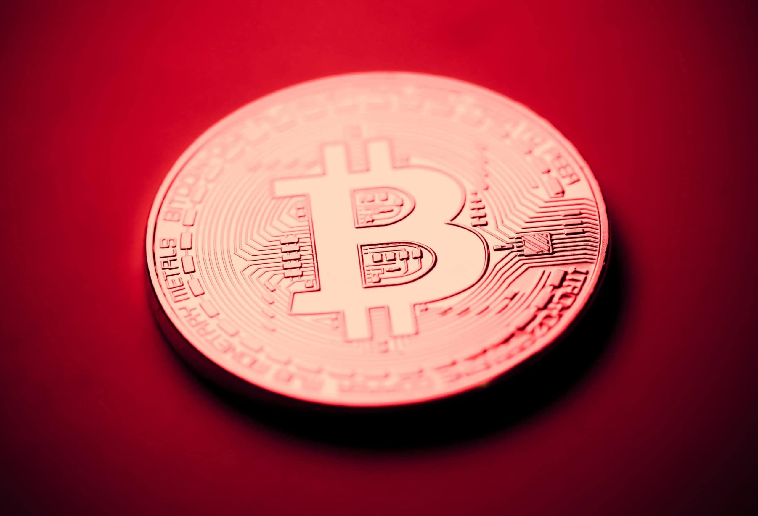 Eine Bitcoin-Münze vor einem roten Hintergrund