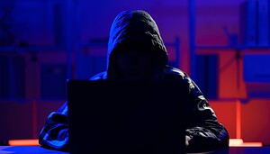Das Bild zeigt eine Hacker vor einem Laptop