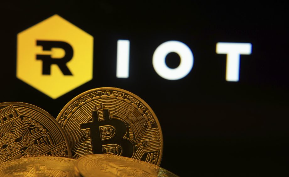 Bitcoin-Münzen vor dem Logo von Riot Platforms. Das Bild symbolisiert das Kerngeschäft des Unternehmens als einer der größten Bitcoin-Miner Nordamerikas.