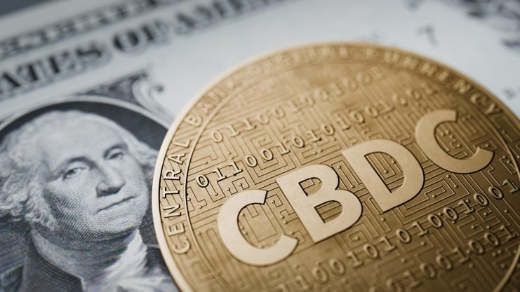 Das Bild zeigt eine CBDC-Münze und im Hintergrund einen Dollar-Schein.