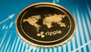 Eine Nahaufnahme einer goldenen Ripple (XRP)-Kryptowährungsmünze mit einem Weltkartenmotiv auf blauem Hintergrund mit Finanzdiagrammlinien.