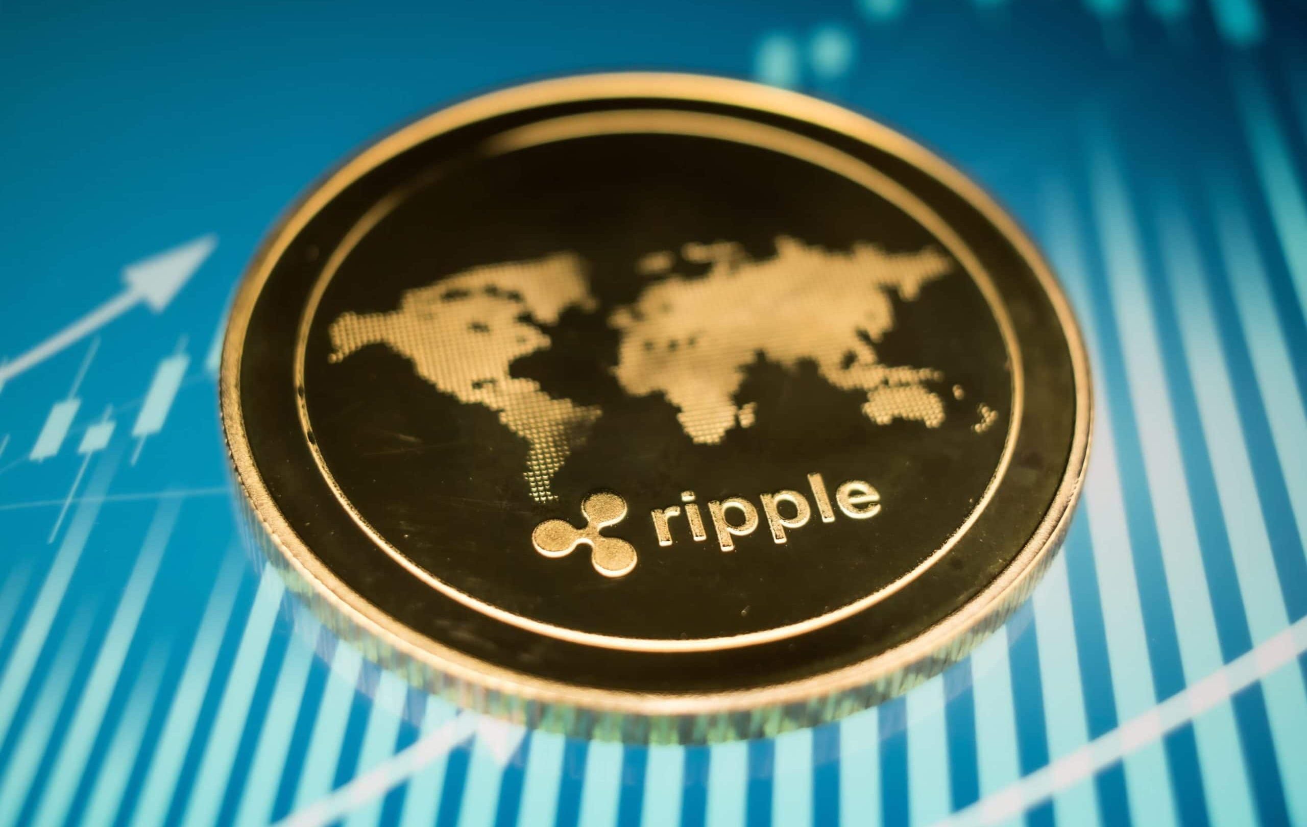 Eine Nahaufnahme einer goldenen Ripple (XRP)-Kryptowährungsmünze mit einem Weltkartenmotiv auf blauem Hintergrund mit Finanzdiagrammlinien.