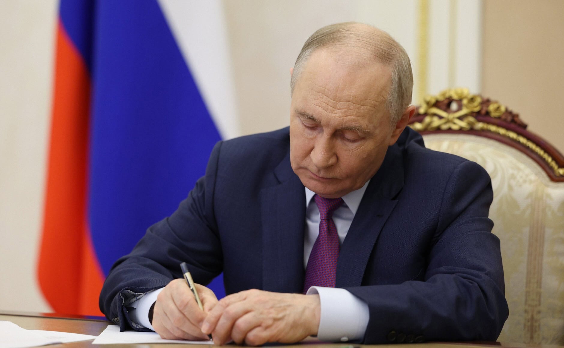 Wladimir Putin schreibt etwas auf einen Zettel.