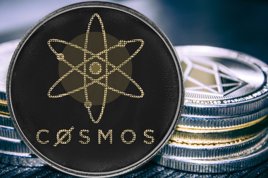 Das Bild zeigt eine Cosmos-(ATOM)-Münze im Vordergrund, die auf mehreren übereinandergestapelten Krypto-Coins liegt. Im Zentrum der schwarzen Münze ist das charakteristische Atom-Symbol von Cosmos abgebildet. Im Hintergrund sind unscharf weitere Kryptowährungen zu erkennen, darunter eine Ethereum-Münze.