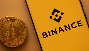Das Bild zeigt das Binance-Logo und eine Bitcoin-Münze