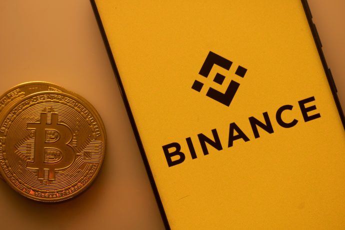 Das Bild zeigt das Binance-Logo und eine Bitcoin-Münze