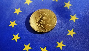 Eine Bitcoin-Münze liegt auf einer Flagge der Europäischen Union mit den zwölf gelben Sternen auf blauem Hintergrund