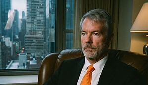 Michael Saylor sitzt in einem Ledersessel mit oranger Krawatte
