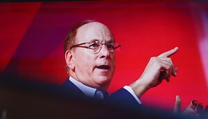 BlackRock CEO Larry Fink gestikuliert mit seiner rechten Hand, während er vor einem roten Hintergrund über die Bitcoin-ETFs von BlackRock spricht.