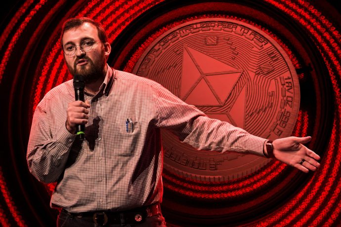 Charles Hoskinson mit Mikrofon vor einer rot beleuchteten Ethereum-Münze.