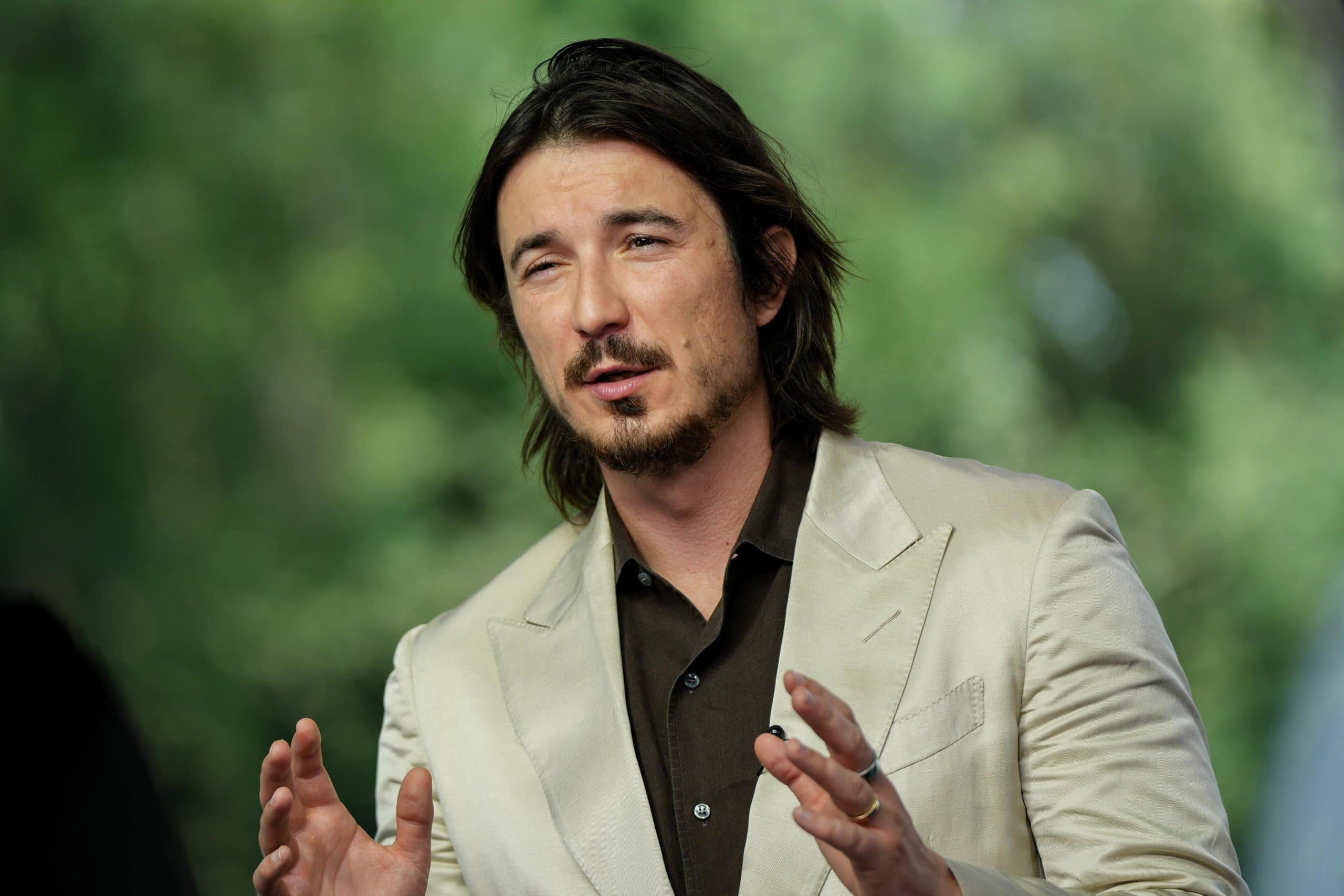 Der Robinhood CEO Vlad Tenev gestikuliert in einem beigen Anzug.