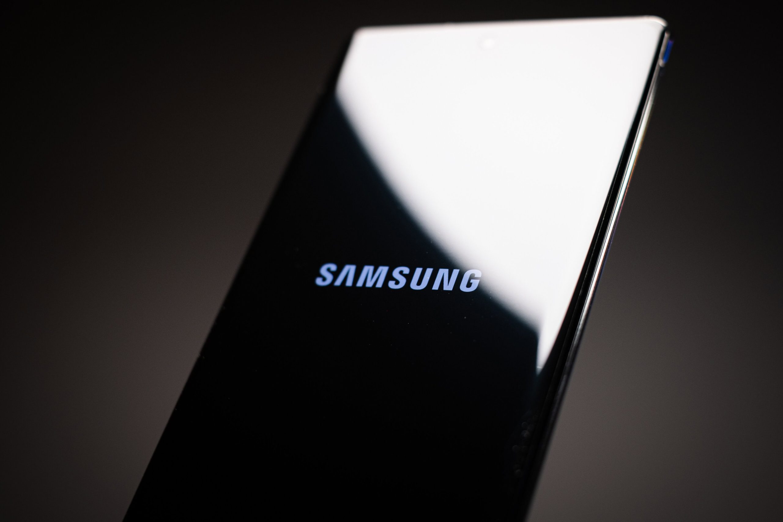 Nahaufnahme eines Samsung-Smartphones, auf dessen Bildschirm das Samsung- und das Coinbase-Logo vor einem dunklen Hintergrund zu sehen sind.