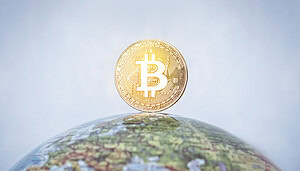 Man sieht einen Globus auf dem eine Bitcoin-Münze steht vor blauem Hintergrund.