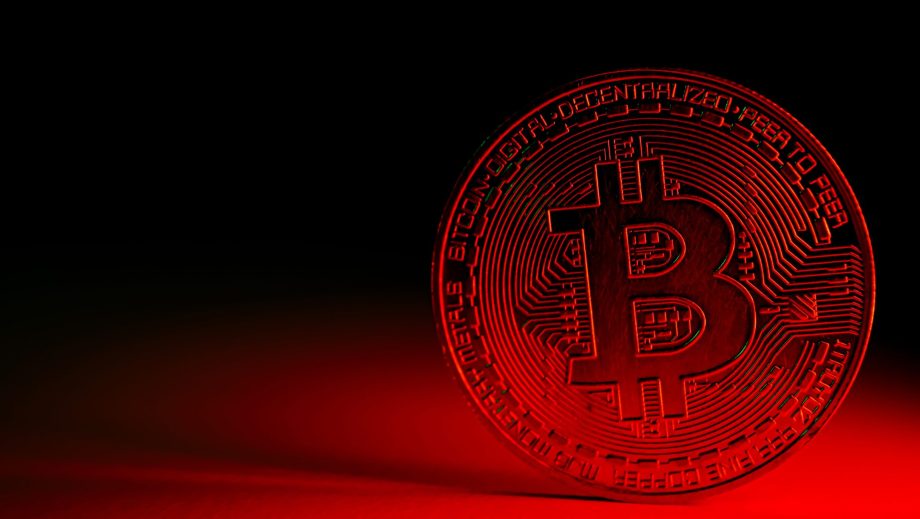 Bitcoin-Münze vor bedrohlichem Hintergrund