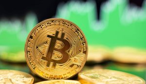 Eine goldene Bitcoin vor einem grünen Charthintergrund.