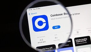 Coinbase-App auf einem Smartphone-Bildschirm unter einer Lupe. Symbolbild für die Kryptobörse Coinbase und den Handel mit digitalen Vermögenswerten.