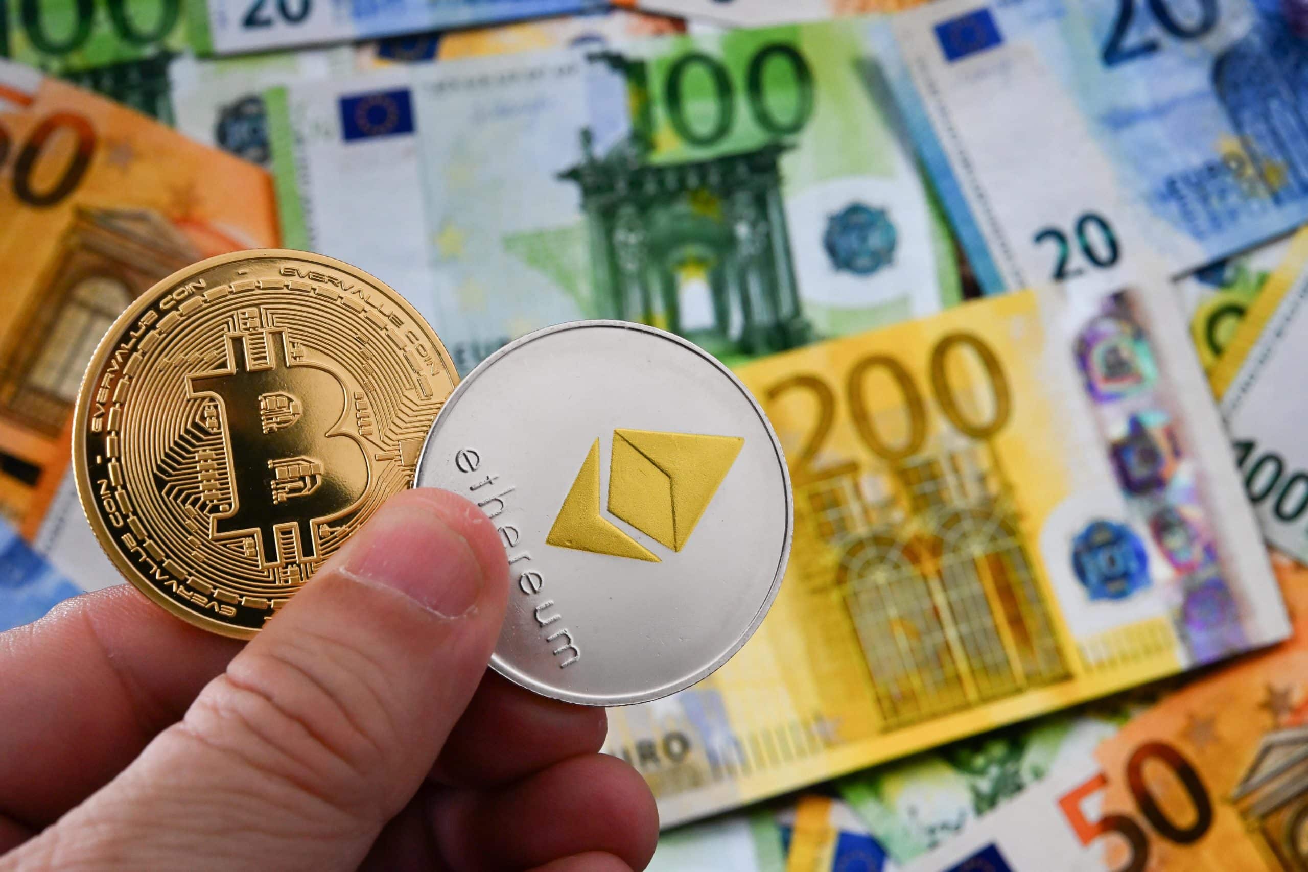 Das Bild zeigt eine Bitcoin- und eine Ethereum-Münze vor Euroscheinen
