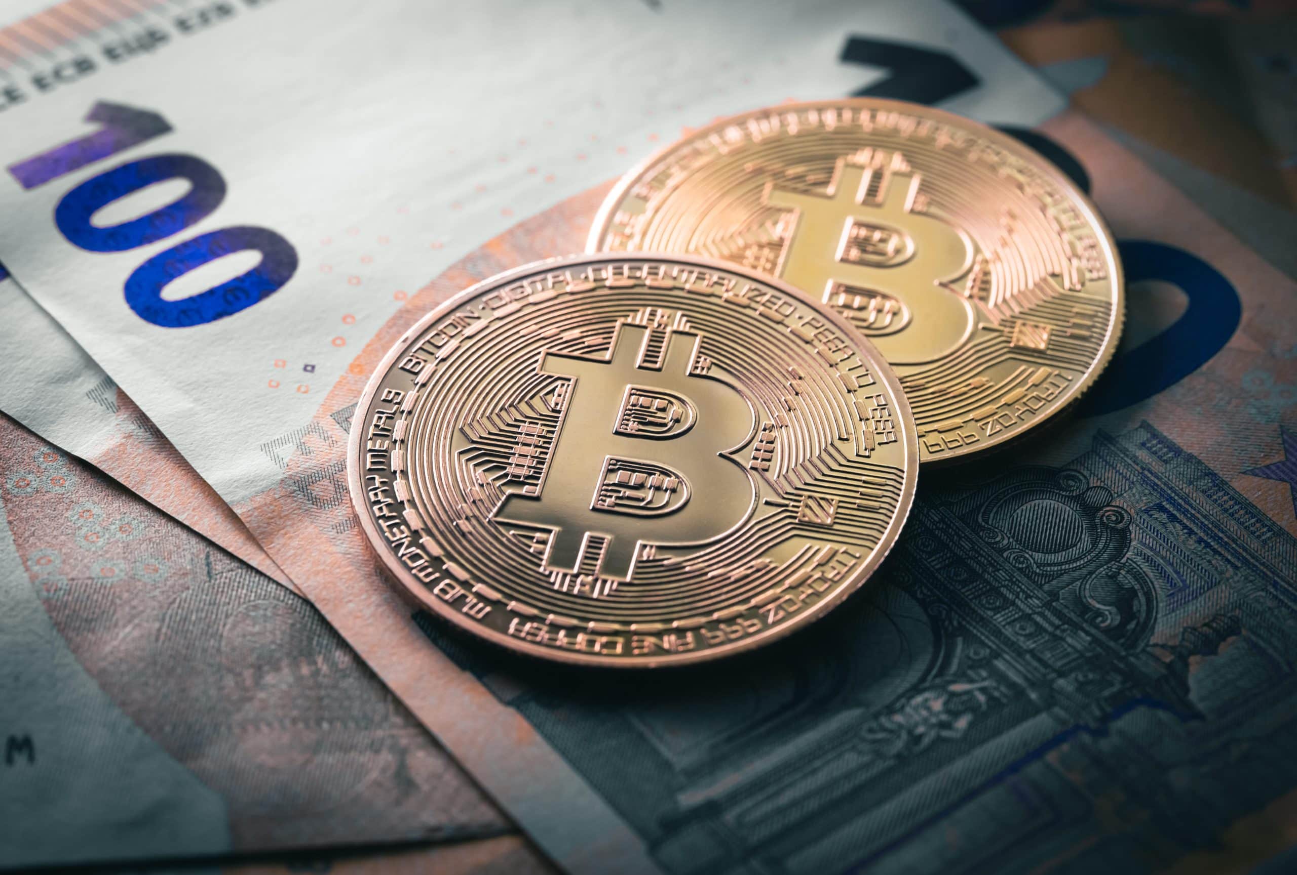 Das Bild zeigt Bitcoin-Münzen auf Euroscheinen