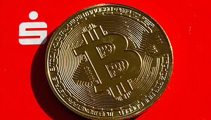 Das Bild zeigt eine Bitcoin-Münze vor dem Logo der Sparkassen