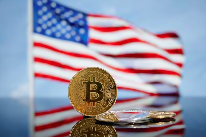 Das Bild zeigt eine Bitcoin-Münze und die Flagge der USA