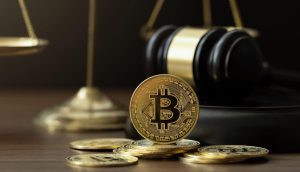 Das Bild zeigt eine Bitcoin-Münze vor einem Gerichtshammer