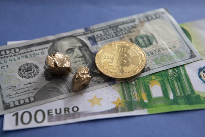 Das Bild zeigt eine goldene Bitcoin-Münze sowie US-Dollar- und Euro-Scheine