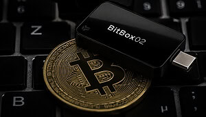 Das Bild zeigt eine Bitcoin-Münze und die BitBox02.