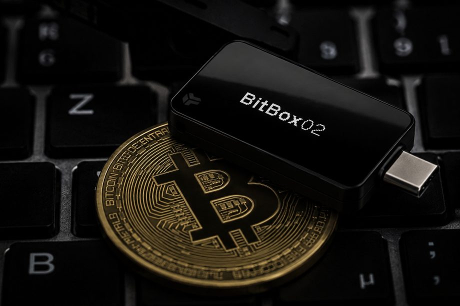 Das Bild zeigt eine Bitcoin-Münze und die BitBox02.