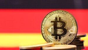Das Bild zeigt eine Bitcoin-Münze vor der Deutschlandflagge