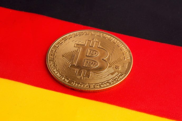 Eine Bitcoin-Münze vor einer Deutschlandflagge
